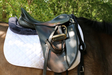 Photo of old leather saddle with stirrups
