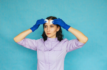 A young girl in blue medical gloves is doing cosmetic procedures. The girl wipes her face with a cotton pad.