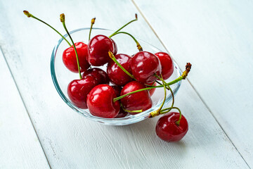 Fototapeta na wymiar ripe cherries in a glass bowl on a white wooden background