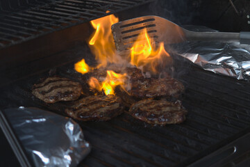 Hamburgers being cooked in flames on the barbeque 