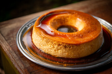 Brazilian gastronomy. Milk pudding with caramelized syrup on wooden table.