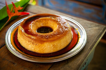 Brazilian gastronomy. Milk pudding with caramelized syrup on wooden table.