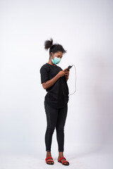 a young african lady wearing a face mask using her mobile phone
