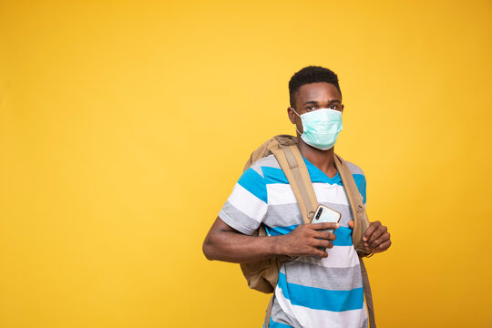 a young black man carrying a backpack and wearing a face mask