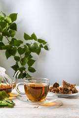 Chaga mushroom drink in a glass cup and teapot. Trendy healthy birch mushrooms. View from above. Vertical orientation