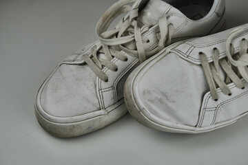 Dirty, used, muddy white dirty pair of shoes on white dirty floor