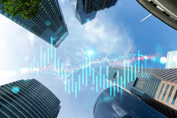 FOREX and stock market chart hologram on low, wide angle view of glass and steel contemporary skyscrapers in financial downtown. The concept of international trading. Double exposure.