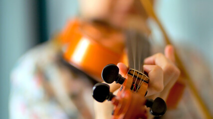 Young woman playing the violin. Hands of musician, close up view. Front view.