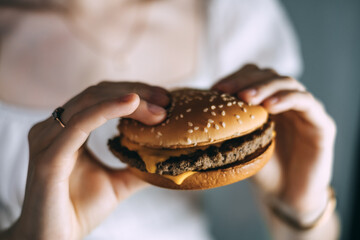 Female hands holding delicious fresh cheesburger. close-up.