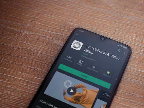 Lod, Israel - July 8, 2020: VSCO - Photo and Video Editor app play store page on the display of a black mobile smartphone on wooden background. Top view flat lay with copy space. 