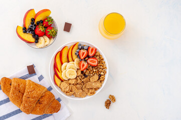 Light summer breakfast muesli with fruits, berries, juice and croissant on a light background. Flatly.