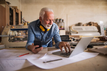 Likeable old engineer looking at the laptop