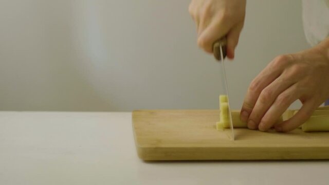 Caucasian Man Cutting Palm Hearts on a Cutting Board at a White Table