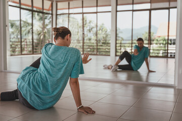 Young woman in a blue t-shirt is dancing in front of a mirror modern contemporary dancing in the dance hall