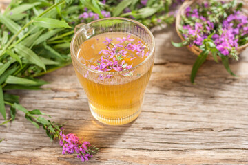 Fireweed is a healthy herbal tea. Mug of traditional russian drink ivan tea on a wooden background...