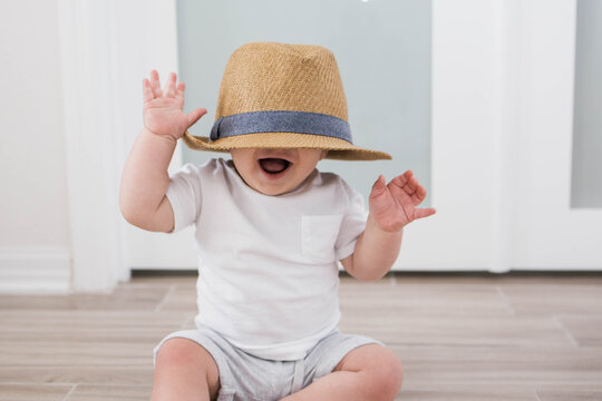baby playing with a straw hat covering his eyes stock photo 