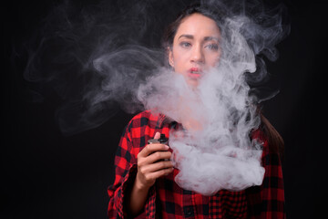 Young beautiful Asian woman vaping against black background