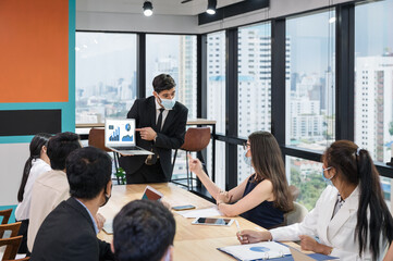 Businessman wearing face mask with presentation of business plan on laptop, corporate business meeting in modern office