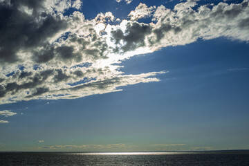 Obraz premium picturesque view of endless seascape with sunbeams reflecting on mirror water surface at cloudy day