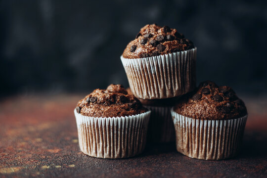 Beautiful chocolate muffins with pieces of chocolate on dark background