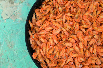 Small shrimp cooked in a black skillet on a blue background