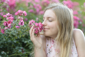 Fototapeta premium Eine junge Frau riecht Blumen 