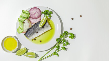 Salted herring with spices, lime slices and red onion rings on a white background. copy space. Flat lay.
