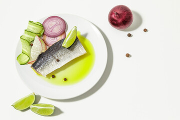 Salted herring with spices, lime slices and red onion rings on a white background. copy space. Flat lay.