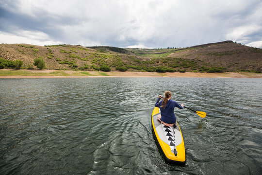rear view of teenage girl paddling on stand up paddle board, Crested Butte, CO.