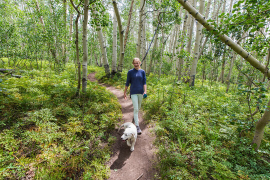 teenage girl walking on nature trail with her English Cream Golden Retriever puppy, Crested Butte, CO.