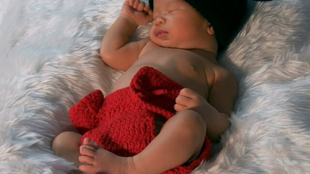 newborn baby in mouse costume sleeping on a fur bed