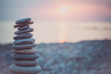 Stones pyramid on sand symbolizing zen, harmony, balance. Ocean at sunset in the background