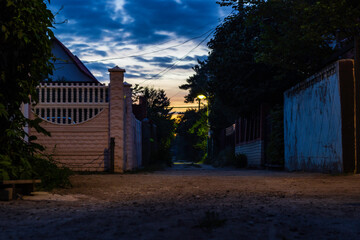 Fototapeta na wymiar Sunset on the street among small houses in russia suburbia.