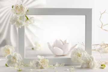 Still life with white flowers and frame on light backdrop. Creative concept for celebration of mother day, birthday, wedding or Valentines day