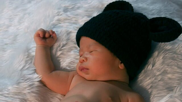newborn baby in mouse costume sleeping on a fur bed