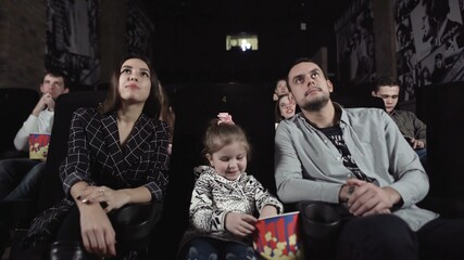 Young man and woman with a child are watching a movie.