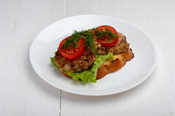 Fototapeta na wymiar cutlet with lettuce and sliced tomato on a toast on a late on white background