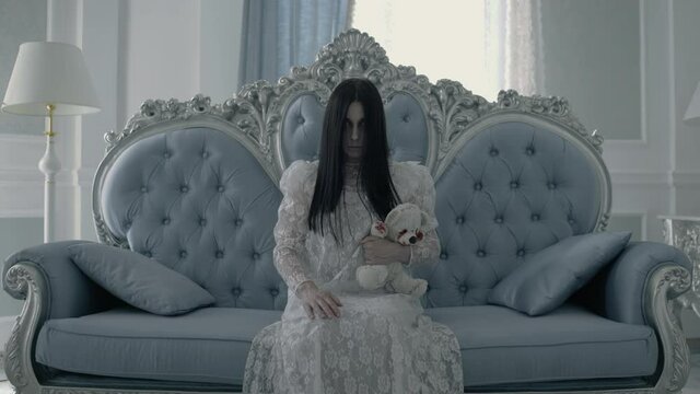 Bride ghost with toy in hand sitting on sofa, demonic spirit of widow, Halloween