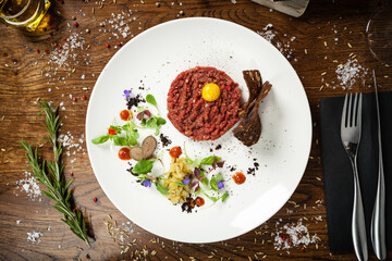 Steak tartare. Horseradish creme, black bread, baguette chips on white plate. Delicious healthy raw meat food closeup served on a table for lunch in modern cuisine gourmet restaurant.