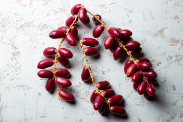 fresh dates fruit on textured white background , red and yellow fresh dates fruit in white plate