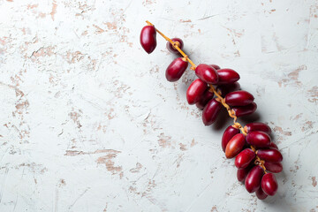 fresh dates fruit on textured white background , red and yellow fresh dates fruit in white plate
