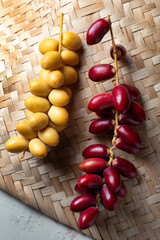 red and yellow fresh dates fruit on bamboo mat , fresh date fruits on bamboo mat 