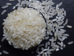 Raw rice in a black bowl Isolated on a blur background. Top view.