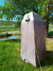 Tourist shower tent by the river. © Khristina