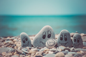 Pebbles with drawn faces in the sand. Father, mother, daughter and son. Family vocation concept.