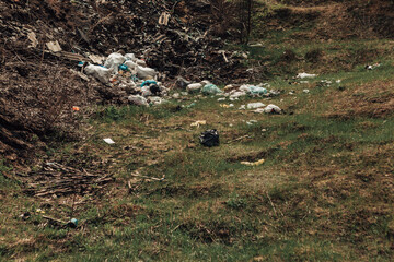 Large pile of garbage in the countryside. Pollution of nature with plastic waste. Green land full of rubbish. 
Dirty trash dump in the village. Scattered litter in the vicinity.

