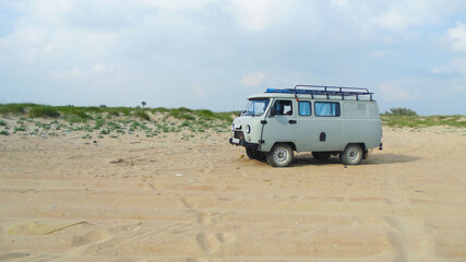 Camper on the background of sand dunes. Summer vacation. The car is gray.