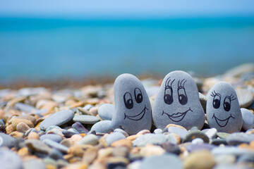 Pebbles with drawn faces in the sand. Father, mother and daughter. Family vocation concept