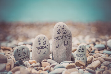 Pebbles with drawn faces in the sand. Father, mother, daughter and son. Family of cats vocation concept