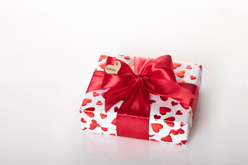 Gift box wrapped in white paper with red heart texture. And wrapped in a pink ribbon.